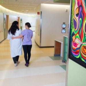 Doula walking with patient down hospital hallway